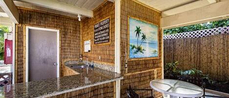 Una zona de bar con pared de madera, un cuadro de una playa y una pequeña mesa redonda.