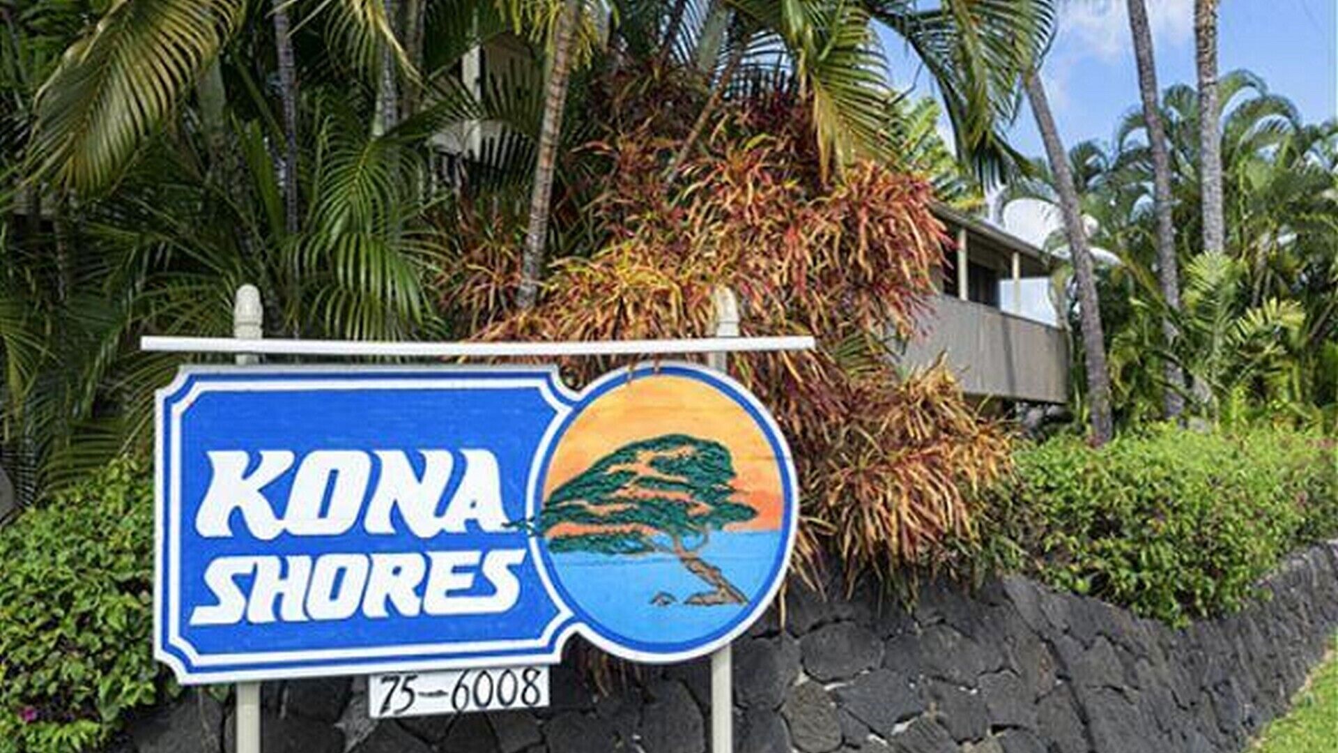 Une enseigne pour Kona Shores, ornée d’une illustration représentant un paysage tropical.
