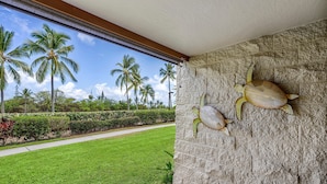 A stone wall with a turtle sculpture, a well-maintained lawn, and palm trees in the background. - Keauhou Punahele#e-102 (Kailua-Kona)