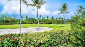 A golf course with palm trees, a well-manicured lawn, and a sandy area. - Keauhou Punahele#e-102 (Kailua-Kona)