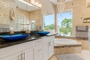 A modern bathroom with a large bathtub, two blue vessel sinks, and a large mirror. - Kona Bubbles (Kailua-Kona)