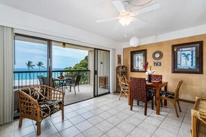Un balcon spacieux offrant une vue sur l’océan, aménagé avec des fauteuils en osier et une table à manger.