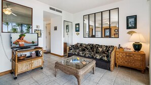 A living room with a sofa, a coffee table, a TV on a stand, and a side table with a lamp.