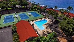 A resort with multiple tennis courts, a swimming pool, and ocean views.