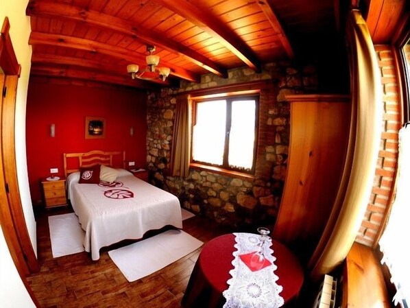 Una habitación acogedora con cama, mesita de noche, pared de piedra y ventana.