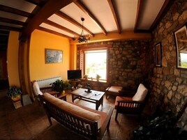 Una sala de estar acogedora con una pared de piedra, un televisor y un ventanal grande.