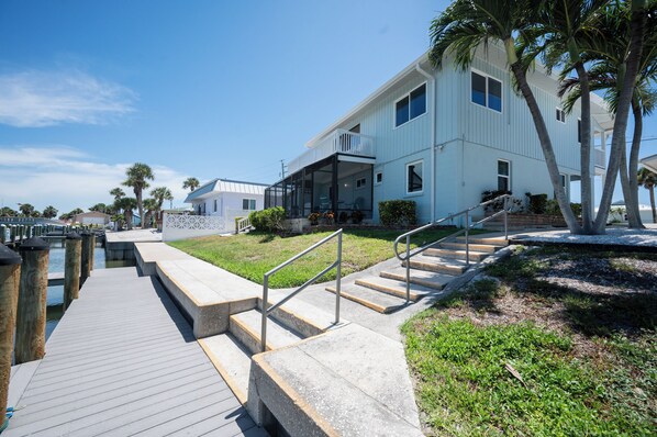 A waterfront property with a wooden dock, concrete steps, and a glass-enclosed balcony. - Cozy cottage on Casey Key (Nokomis)
