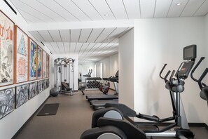 A gym with treadmills, weight machines, and a wall of artwork. - The Williams Inn (Williamstown)