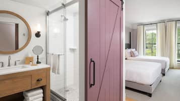 A hotel room with a bathroom, a bed, and a large window.