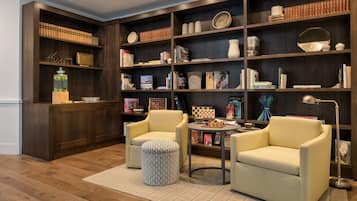Un coin lecture confortable avec une bibliothèque, deux fauteuils, une table ronde et un lampadaire.