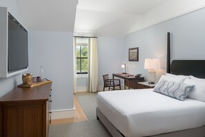 A hotel room with a bed, desk, chair, lamp, and a TV on the wall. - The Williams Inn (Williamstown)