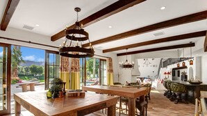 Un comedor amplio con una gran mesa de madera y sillas, un candelabro y vistas al exterior.