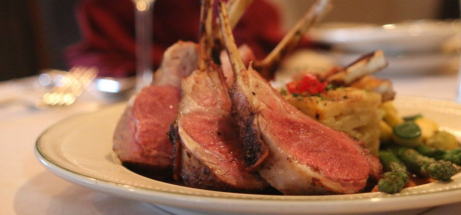 Ein Teller mit Lammkoteletts, Bratkartoffeln und Spargel.