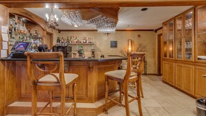 A bar area with wooden bar stools, a cash register, and a variety of liquor bottles. - The Whispering Pines Inn Bed & Breakfast (Norman)