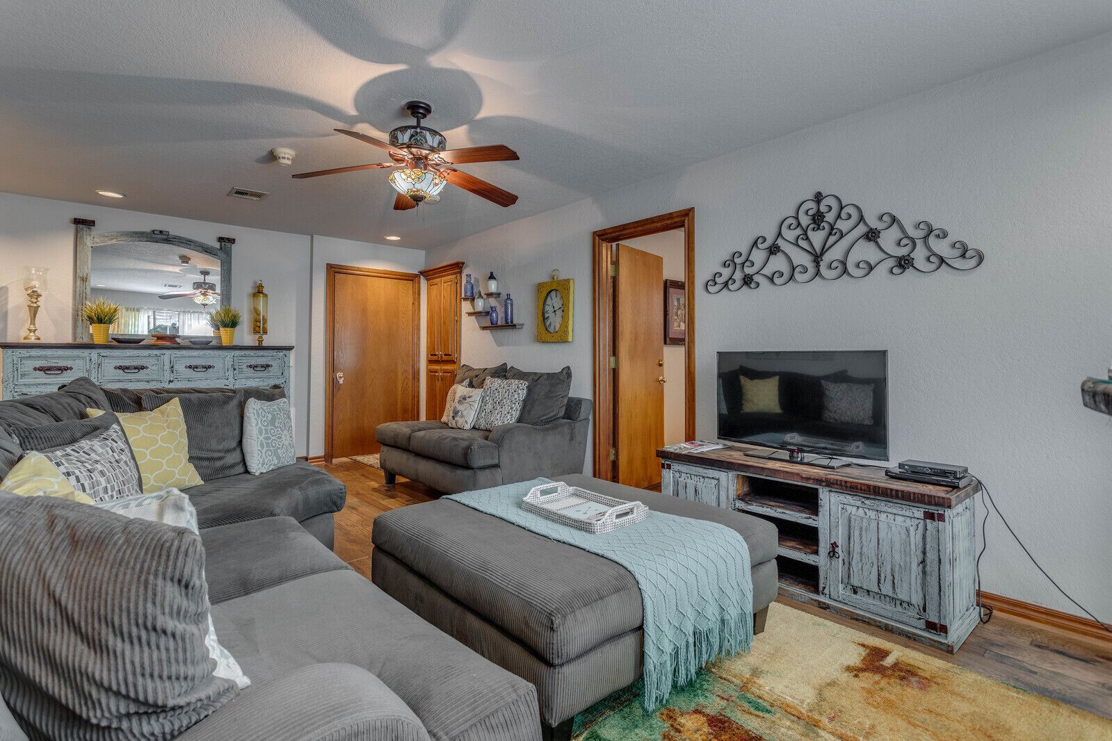 A living room with a ceiling fan, a TV, and a rustic entertainment unit.