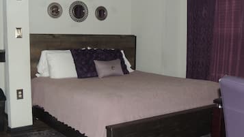A bedroom with a wooden bed, a headboard, a patterned rug, and a wall-mounted light fixture.
