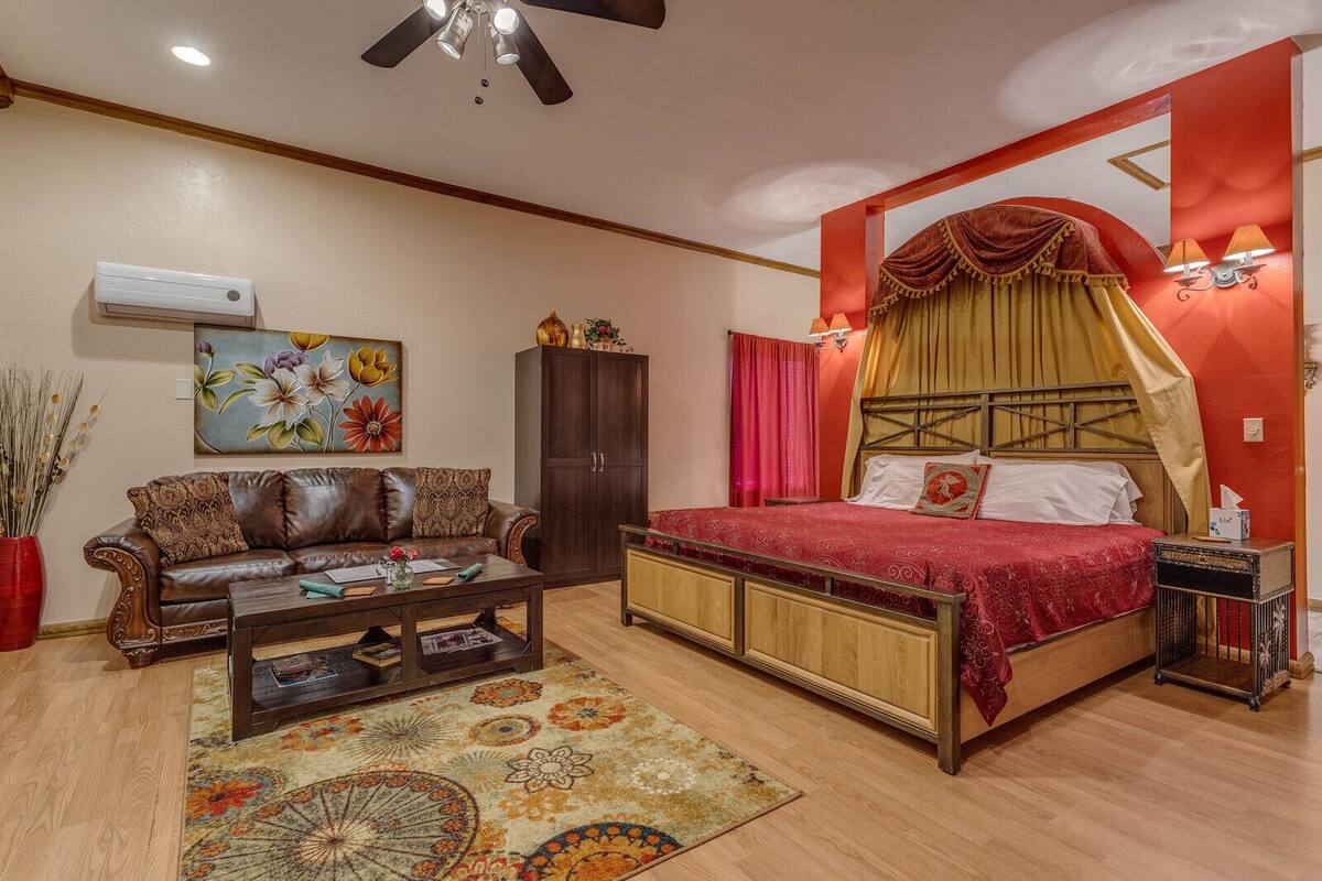 A bedroom with a bed, a sofa, a cabinet, and a ceiling fan.