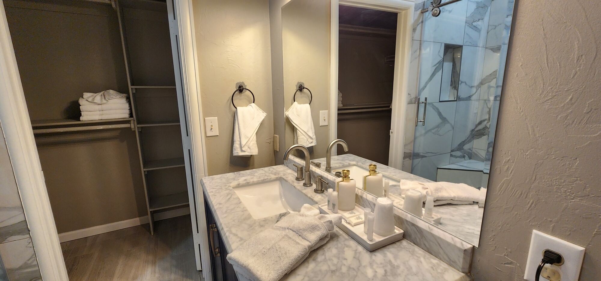 A bathroom with a marble countertop, a sink, a mirror, and a towel rack.