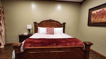 A bedroom with a wooden bed, a nightstand with a lamp, and a wall-mounted painting.