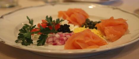 A plate with smoked salmon, diced onions, parsley, and a small amount of black caviar.