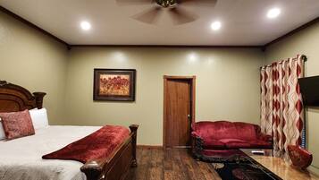 A bedroom with a bed, a red armchair, a wooden door, and a painting on the wall.