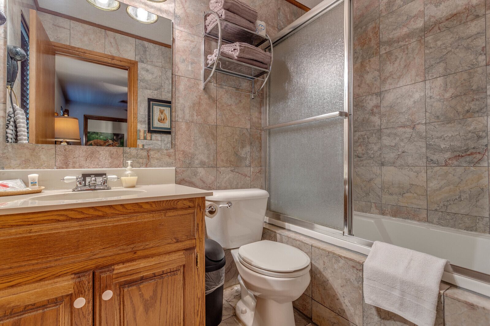 Une salle de bain avec un mur en marbre, un meuble-lavabo en bois, des toilettes et un espace douche.