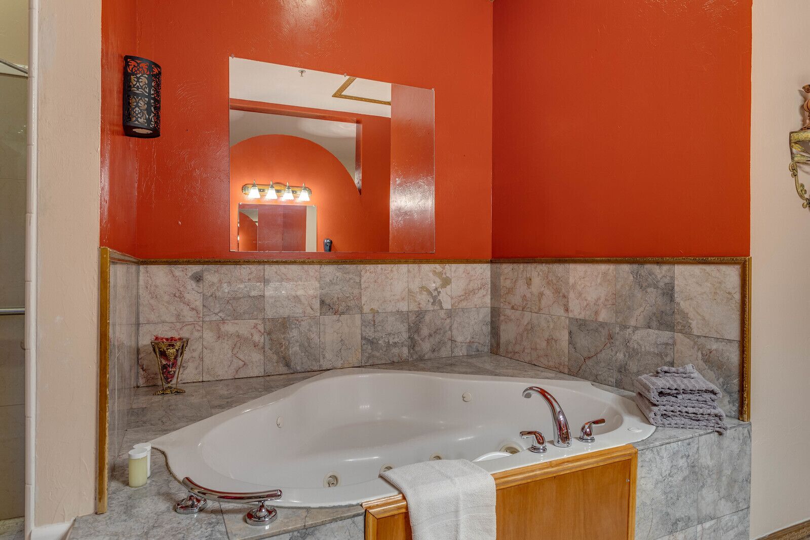 A bathroom with a large bathtub, marble tiles, and an orange wall.