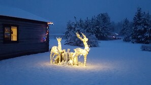 A cabin with a snow-covered landscape and illuminated reindeer figures.