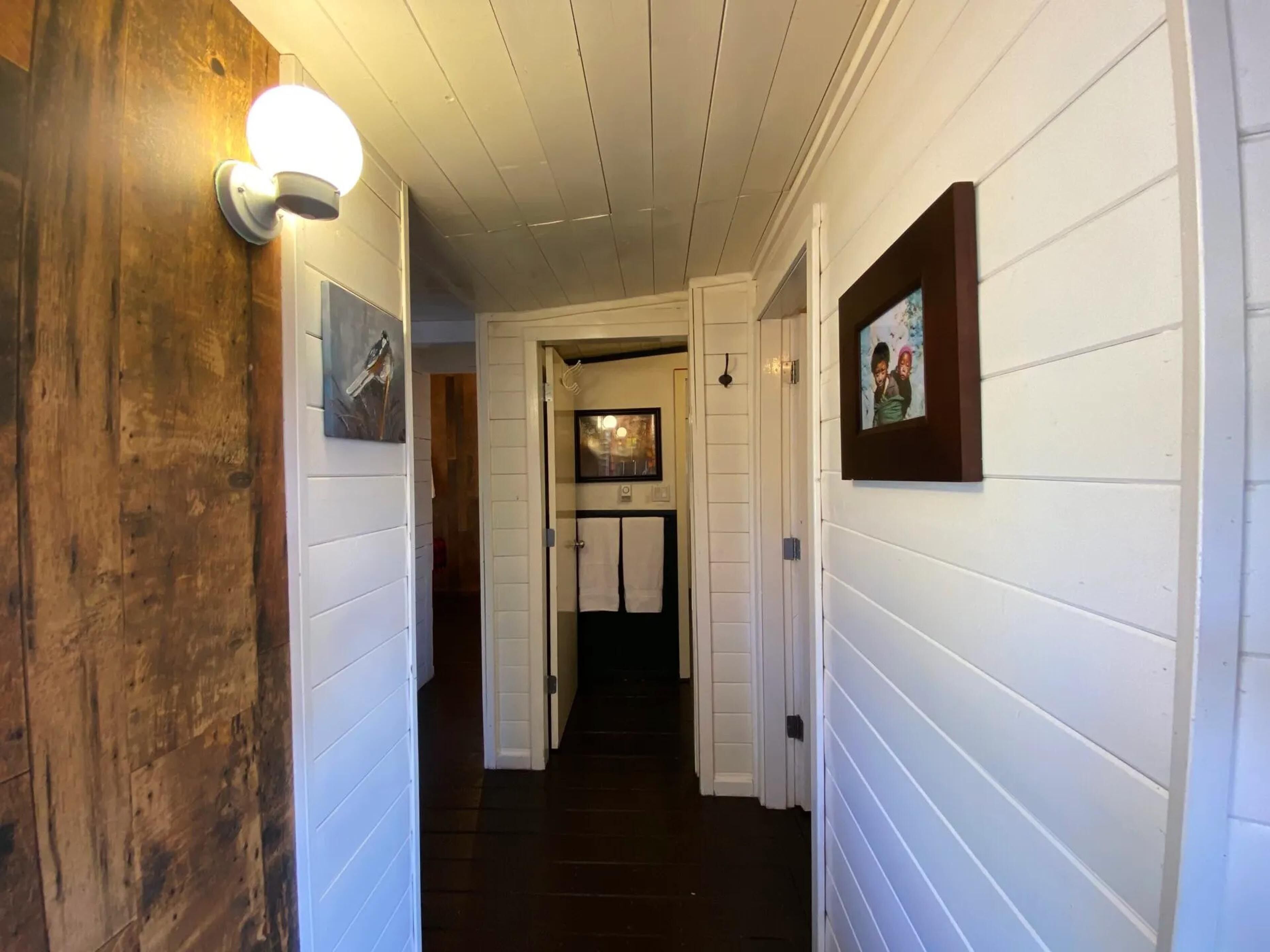 A hallway with white paneling and wooden accents, leading to a door at the end.