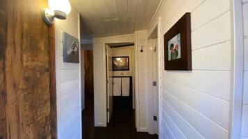 A hallway with white paneling and wooden accents, leading to a door at the end.
