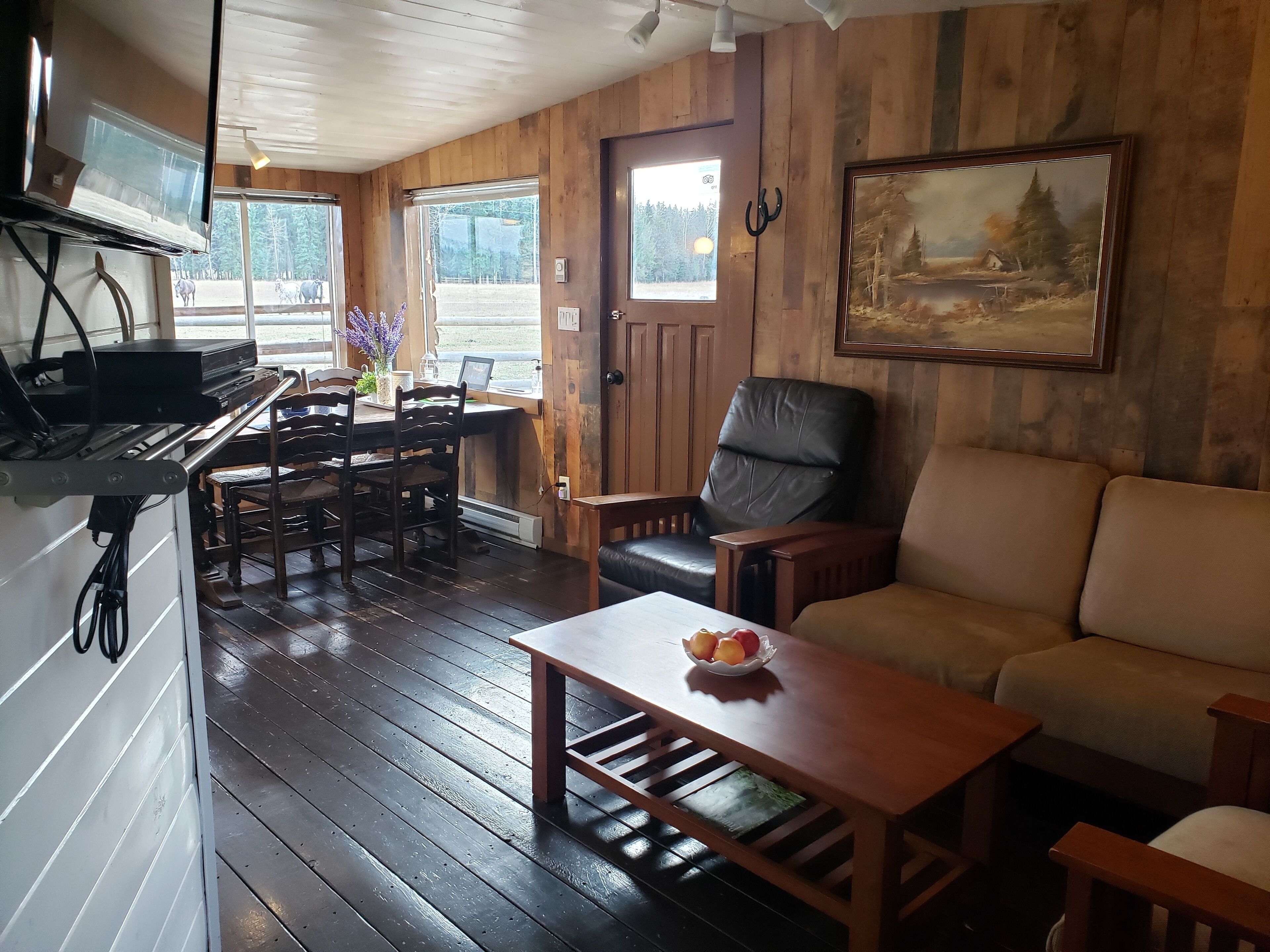 A cozy room with a wooden interior, a sofa, a coffee table, a desk with a computer, and a chair.