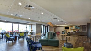 A spacious indoor area with seating arrangements, a counter, and large windows.