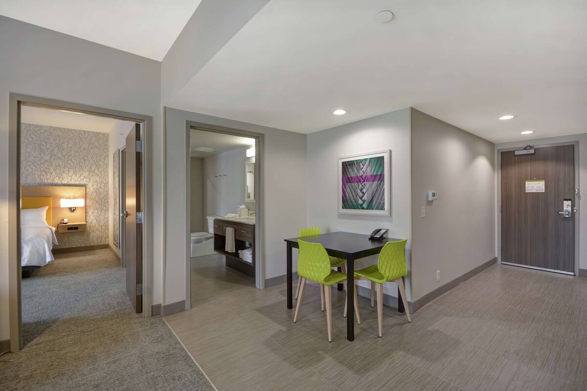Une chambre d’hôtel avec un lit, une table de chevet et une salle de bain visible à travers une porte ouverte.