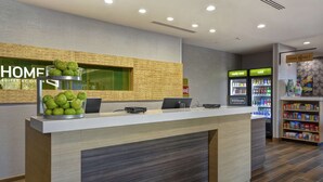 A hotel reception desk with a modern design, a fruit bowl, a laptop, and a sign indicating 'Hilton Honors'.