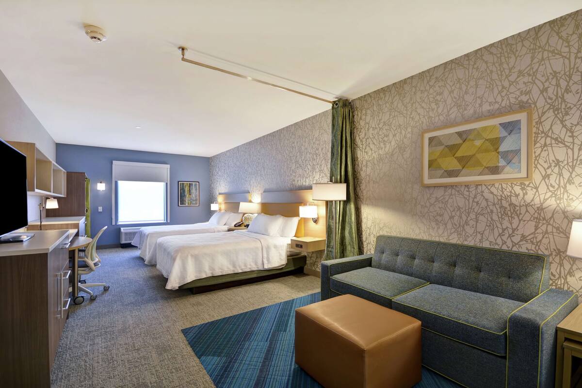 Une chambre d’hôtel avec deux lits, un bureau, un canapé et une télévision.