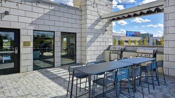 An outdoor patio with a grill, tables, and chairs.