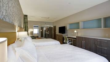 A hotel room with two beds, a desk, a TV, and a bathroom visible in the background.