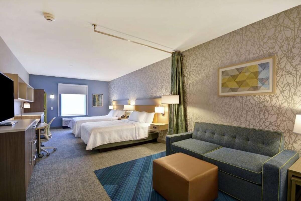 Une chambre d’hôtel avec deux lits, un canapé, un bureau et une télévision.