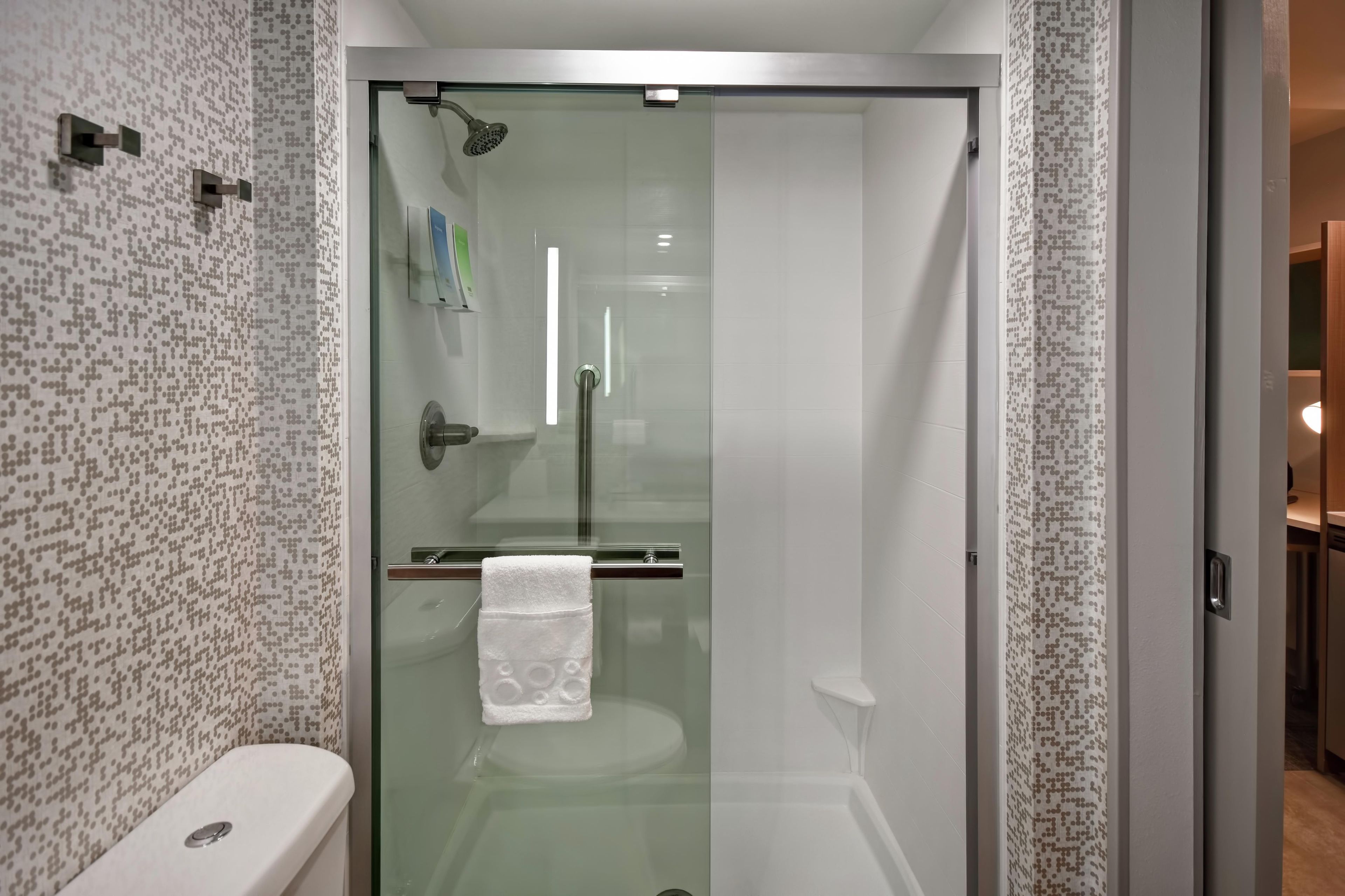 Une salle de bain moderne avec une douche à parois de verre, des toilettes et un porte-serviettes.