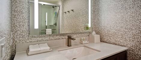 Une salle de bain moderne avec un grand miroir, un lavabo et un porte-serviettes.