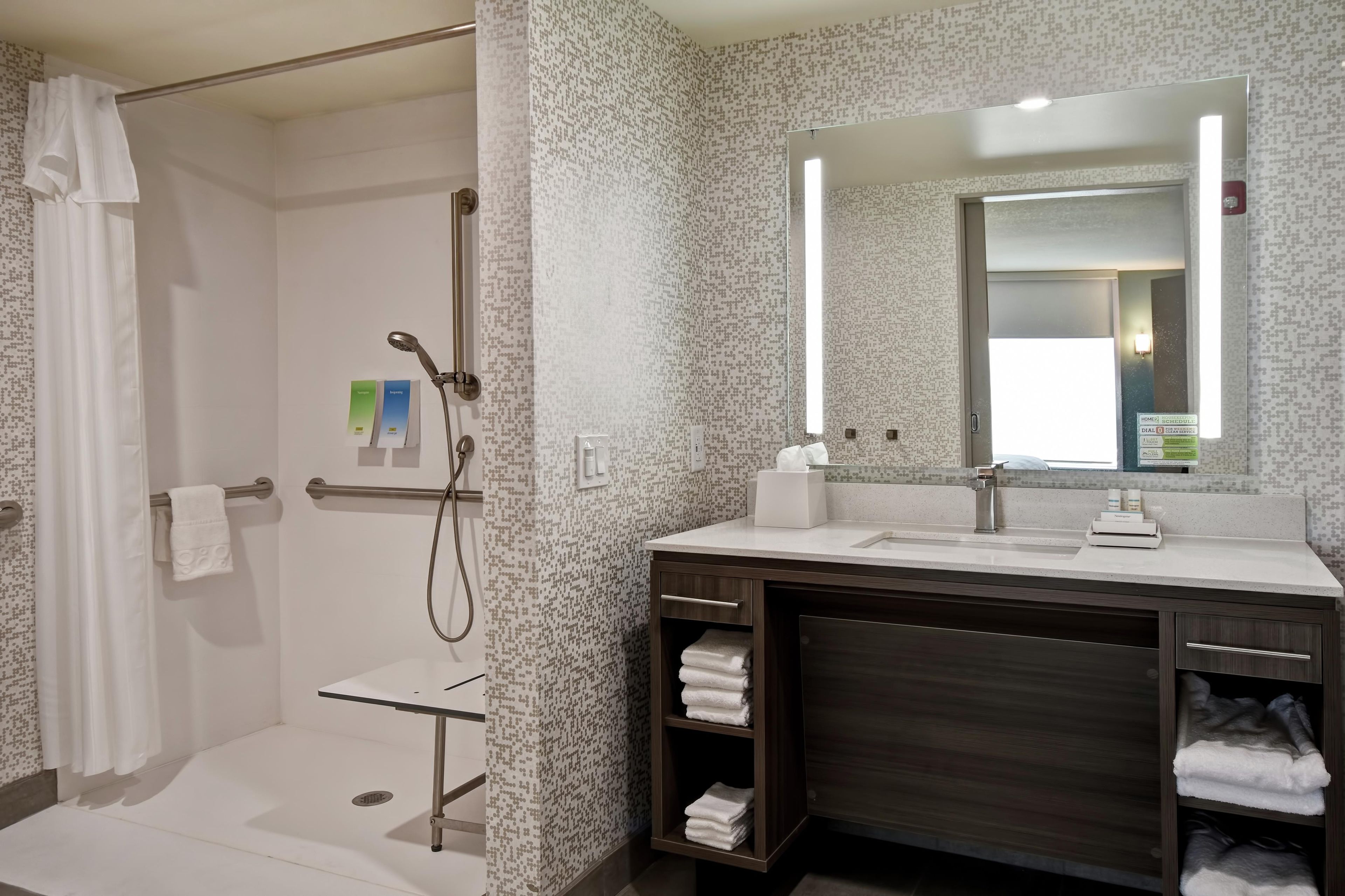 Un baño moderno con ducha, lavabo, espejo y toallero.