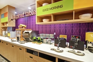 Una barra de desayuno con un letrero que dice 'Good Morning', diversas opciones de comida y una máquina de café.