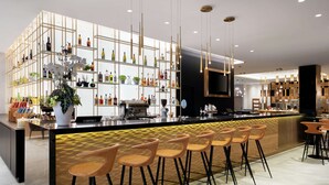 Zona de bar moderna amb una illa central, tamborets i una varietat de garrafes a les prestatgeries.
