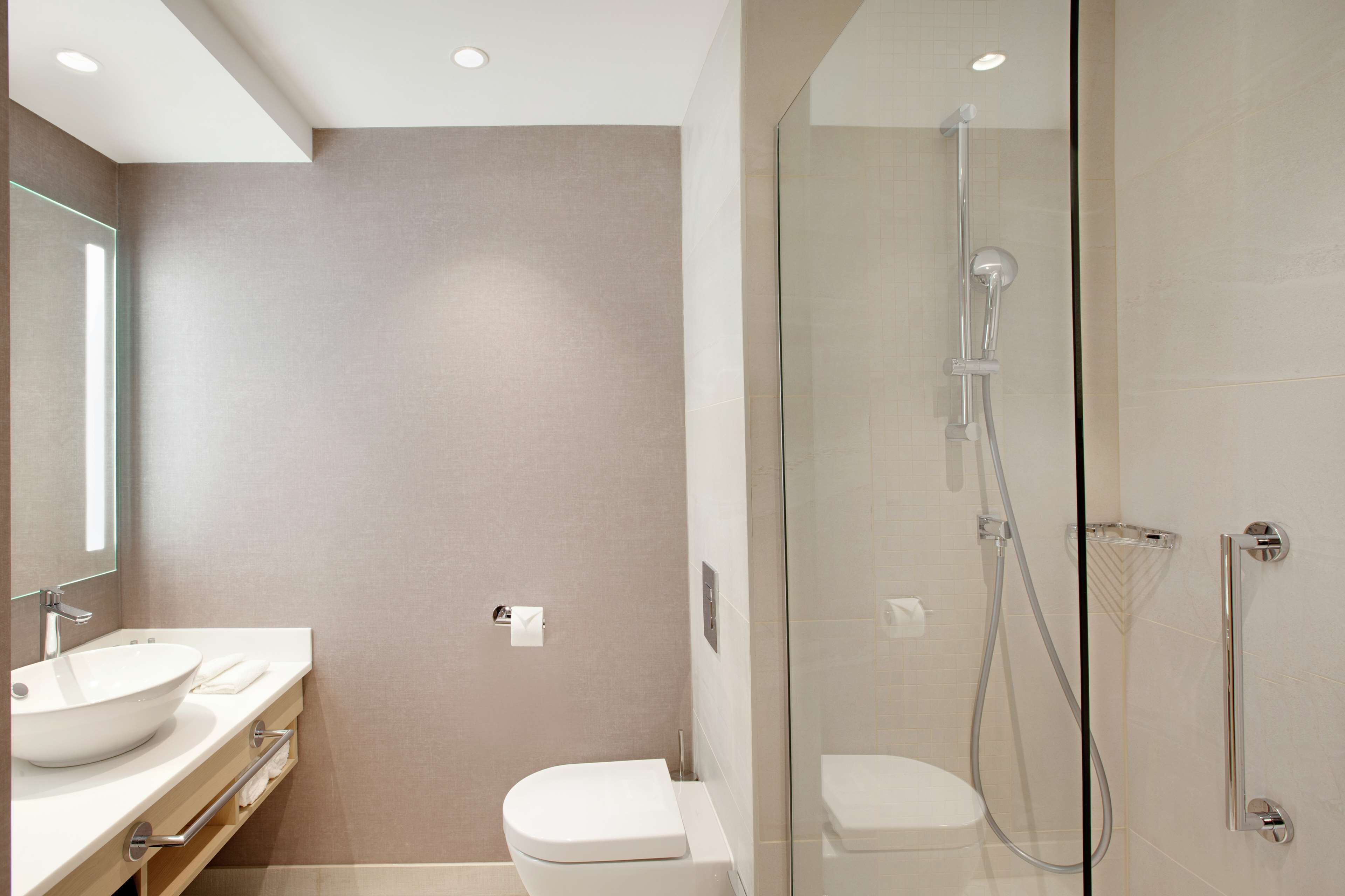 A modern bathroom with a glass-enclosed shower, a white sink, and a toilet.