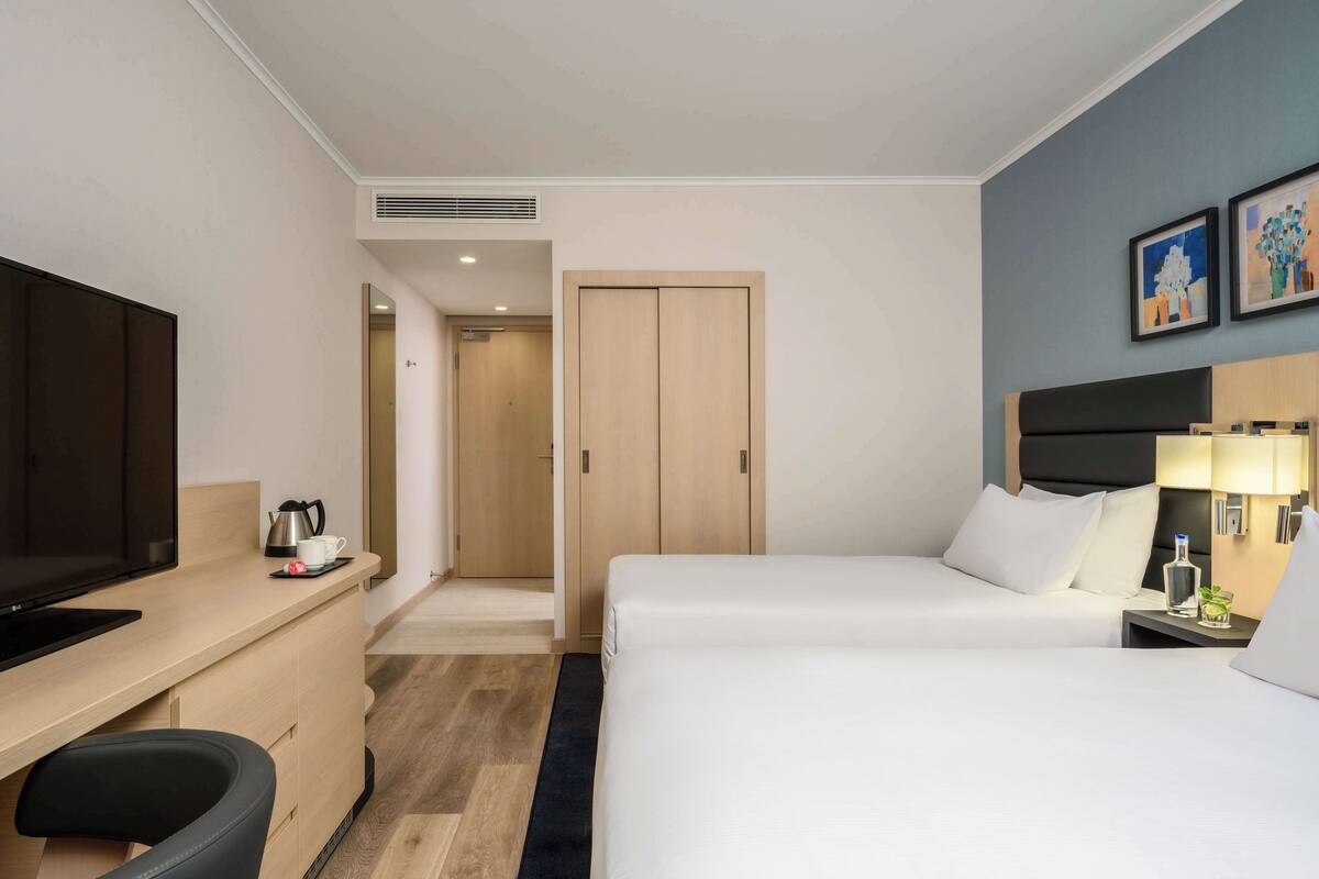 Una habitación de hotel con cama, escritorio, televisor y armario.