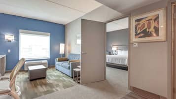 Habitación de hotel con una ventana grande, un sofá, una silla, una mesita y una cama.