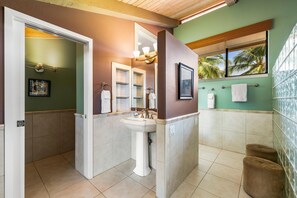 A bathroom with a pedestal sink, a large mirror, and a window with a view of palm trees. - Keauhou Kona Surf & Racquet Club #5-303 (Kailua-Kona)