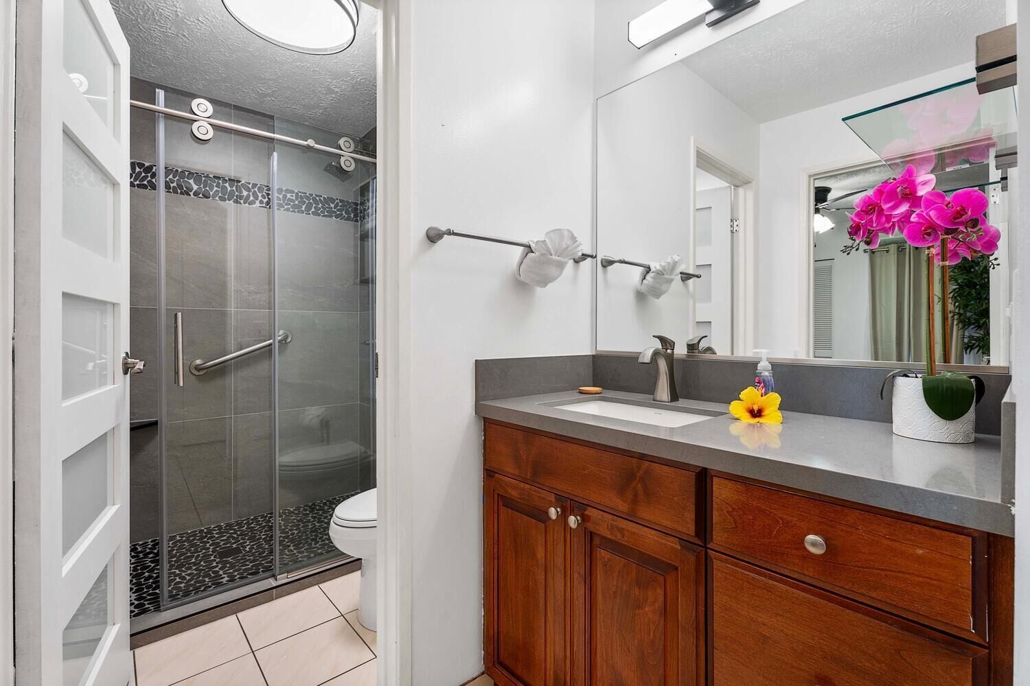 A modern bathroom with a glass-enclosed shower, a vanity with a mirror, and a toilet.