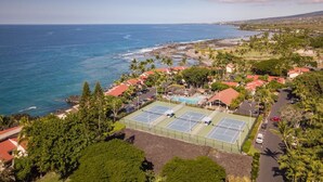 Ein Küstenwohngebiet mit Tennisplätzen, einem Schwimmbad und Häusern mit roten Dächern.