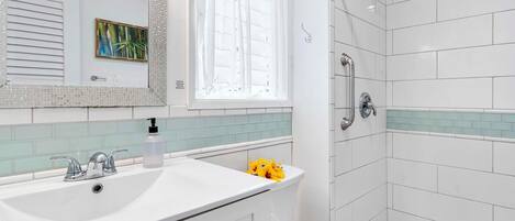 A modern bathroom with a white sink, a toilet, and a shower area.